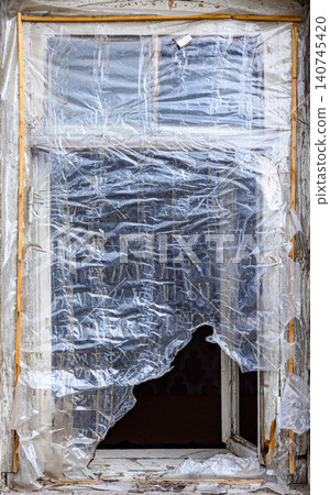Old window frame cracked, wrapped in plastic on stone building Old window frame cracked, wrapped in plastic on stone building 140745420