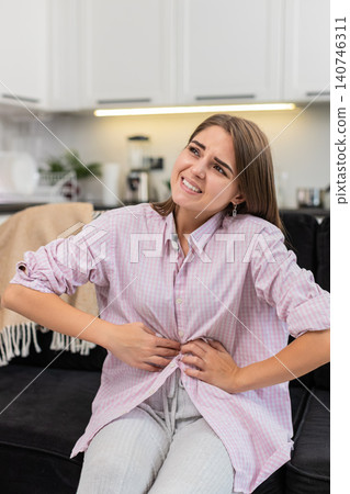 Young woman holds stomach with cramps after greasy foods or period pains rests and seeks for relief Young woman holds stomach with cramps after greasy foods or period pains rests and seeks for relief 140746311