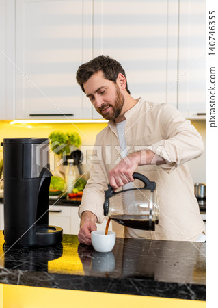 Middle-aged man pouring hot coffee in home kitchen smiling satisfied enjoying morning caffeine break Middle-aged man pouring hot coffee in home kitchen smiling satisfied enjoying morning caffeine break 140746355