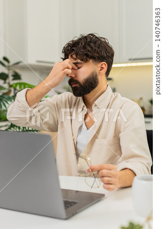 Indian man tired remote worker with laptop in glasses rubbing eyes fighting fatigue continues typing Indian man tired remote worker with laptop in glasses rubbing eyes fighting fatigue continues typing 140746363