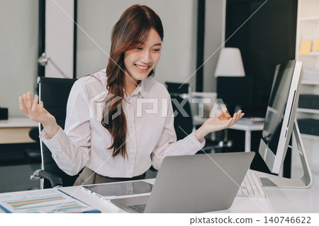 Young businesswoman professional employee using pc doing online banking analysing at workplace. Asian middle-aged business woman working on laptop computer in office, taking notes. Banner, copy space Young businesswoman professional employee using pc doing online banking analysing at workplace. Asian middle-aged business woman working on laptop computer in office, taking notes. Banner, copy space 140746622