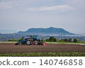 A tractor working with Mount Hakodate in the background. 140746858
