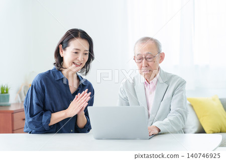 An elderly man learning to use a computer and his daughter teaching him. 140746925