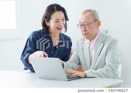 一位老人在女兒的指導下學習使用電腦。 140746927