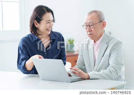 An elderly man learning to use a computer and his daughter teaching him. 140746928
