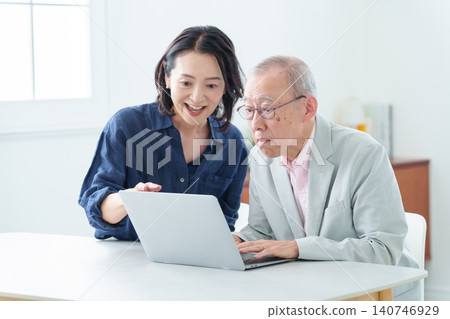 An elderly man learning to use a computer and his daughter teaching him. 140746929