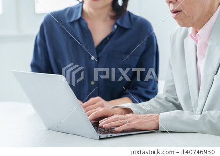 An elderly man learning to use a computer and his daughter teaching him. 140746930
