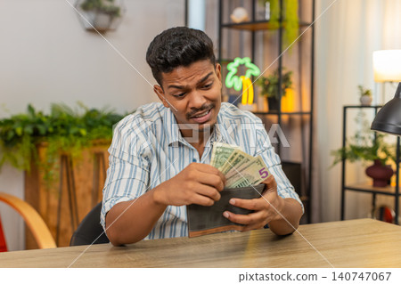 Indian man checks wallet sees small bills low cash sighs plans savings budget goal debt recovery aim Indian man checks wallet sees small bills low cash sighs plans savings budget goal debt recovery aim 140747067