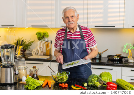 Senior old man mixing cucumber salad in home kitchen for diet plan and healthy nutrition lifestyle Senior old man mixing cucumber salad in home kitchen for diet plan and healthy nutrition lifestyle 140747068