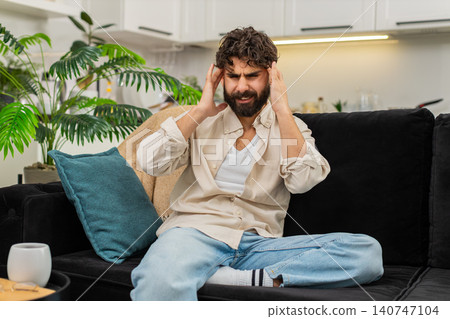 Indian man pressing fingers to temples suffering headache migraine pain stress worrying about health Indian man pressing fingers to temples suffering headache migraine pain stress worrying about health 140747104
