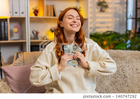 Young woman on home sofa counting cash smiling while dreaming of purchase vacation or great success Young woman on home sofa counting cash smiling while dreaming of purchase vacation or great success 140747292