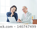 An elderly man using a computer with a troubled expression. 140747499