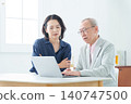 An elderly man using a computer with a troubled expression. 140747500