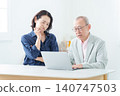 An elderly man using a computer with a troubled expression. 140747503