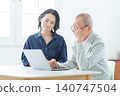 An elderly man using a computer with a troubled expression. 140747504