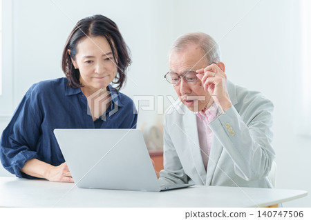 An elderly man using a computer with a troubled expression. 140747506