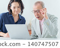 An elderly man using a computer with a troubled expression. 140747507