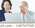 An elderly man using a computer with a troubled expression. 140747509