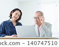 An elderly man using a computer with a troubled expression. 140747510