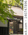 A temple landscape featuring green maple leaves and traditional Japanese architecture. 140747896