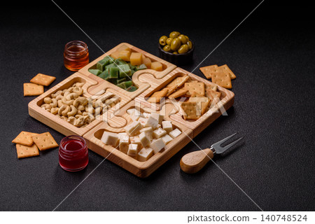 A tray with cubes of mozzarella, and Parmesan cheese, nuts, and crackers. Cheese, crackers, and nuts 140748524