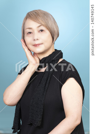 Portrait studio shoot of a senior woman, with a light blue background. Portrait studio shoot of a senior woman, with a light blue background. 140749145
