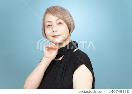 Portrait studio shoot of a senior woman, with a light blue background. 140749158