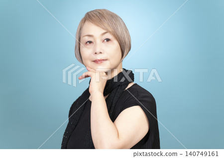 Portrait studio shoot of a senior woman, with a light blue background. Portrait studio shoot of a senior woman, with a light blue background. 140749161