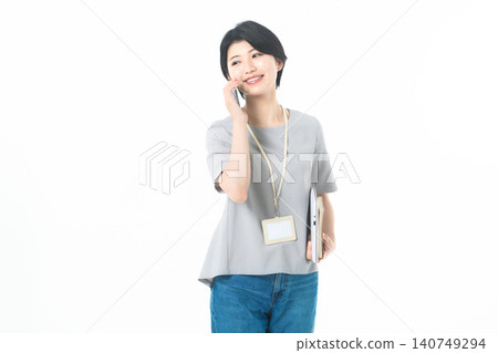 一位年輕女子麵帶微笑,側身看向一邊,在白色背景前打電話。 一位年輕女子麵帶微笑,側身看向一邊,在白色背景前打電話。 140749294