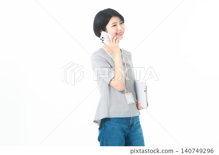 A young woman, facing sideways, smiles while talking on her smartphone against a white background. A young woman, facing sideways, smiles while talking on her smartphone against a white background. 140749296