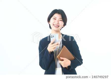 A young woman in a suit, smiling, holding her smartphone and notebook. A young woman in a suit, smiling, holding her smartphone and notebook. 140749297