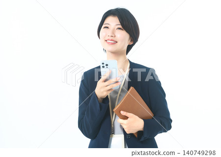 A young woman in a suit, holding her smartphone and looking up, deep in thought. A young woman in a suit, holding her smartphone and looking up, deep in thought. 140749298