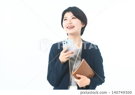 A smiling businesswoman looking up while holding her smartphone. A smiling businesswoman looking up while holding her smartphone. 140749300