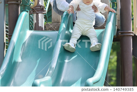 A daughter and her father enjoying a slide in the park. A daughter and her father enjoying a slide in the park. 140749385