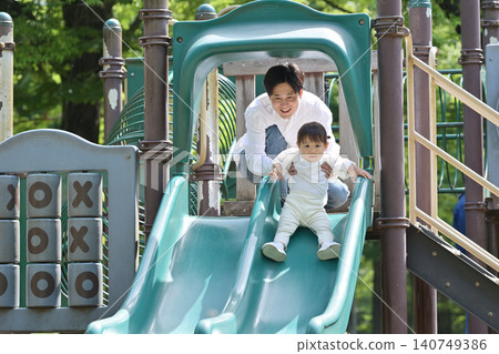 女兒和父親在公園裡玩滑梯。 140749386