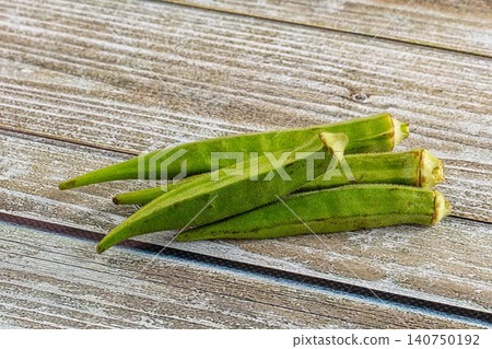 Fresh green okra pods on weathered wooden surface Fresh green okra pods on weathered wooden surface 140750192
