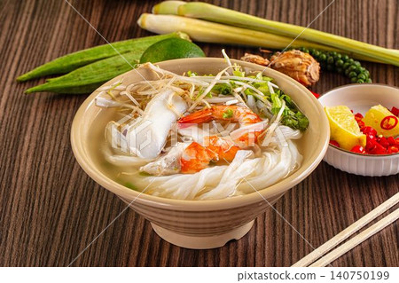 Seafood noodle soup with shrimp squid bean sprouts and lime chili garnish on wooden table Seafood noodle soup with shrimp squid bean sprouts and lime chili garnish on wooden table 140750199