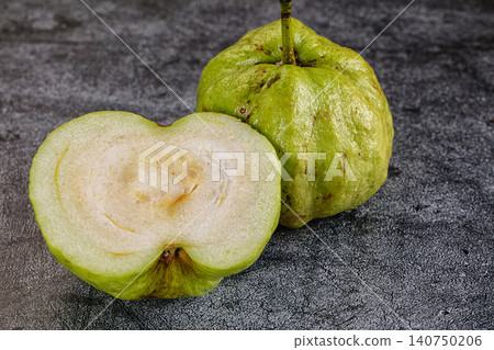 Fresh green guava fruit sliced open on dark textured surface Fresh green guava fruit sliced open on dark textured surface 140750206