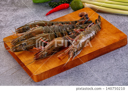 Fresh raw tiger prawns on wooden cutting board with chili lime and lemongrass 140750210