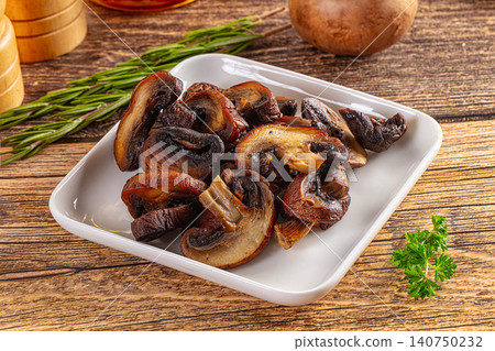 Grilled mushrooms on white plate with rosemary and parsley on rustic wood table Grilled mushrooms on white plate with rosemary and parsley on rustic wood table 140750232
