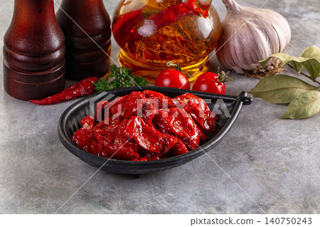 Sun dried tomatoes in black bowl with garlic olive oil and spices on stone surface Sun dried tomatoes in black bowl with garlic olive oil and spices on stone surface 140750243