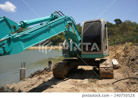 Building process city levee. Excavator dredging pond bank Building process city levee. Excavator dredging pond bank 140750528