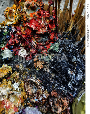 Vibrant messy artist palette covered in glossy paint, scattered brushes and tubes, dried paint Vibrant messy artist palette covered in glossy paint, scattered brushes and tubes, dried paint 140750535