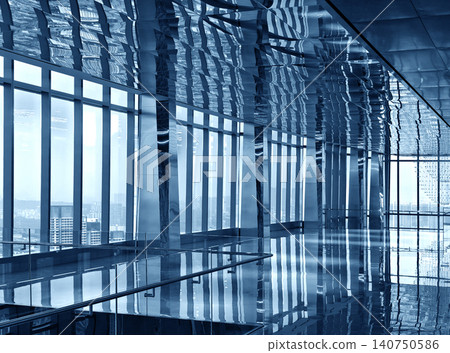 Spacious glass atrium with reflections on polished floor and panoramic windows. Empty lobby features Spacious glass atrium with reflections on polished floor and panoramic windows. Empty lobby features 140750586
