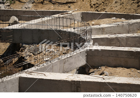 Building process city levee. Exposed foundation rebar grid at site, standing formwork and concrete footings Building process city levee. Exposed foundation rebar grid at site, standing formwork and concrete footings 140750620