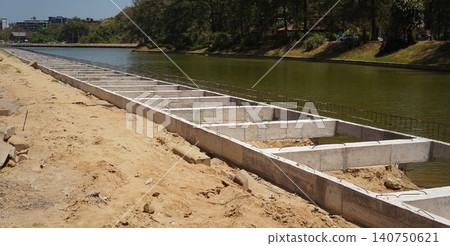 Building process city levee. Exposed foundation rebar grid at site, standing formwork and concrete footings Building process city levee. Exposed foundation rebar grid at site, standing formwork and concrete footings 140750621