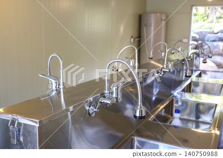 Row of Clean Stainless Steel Sinks and Faucets in a Public Facility 140750988