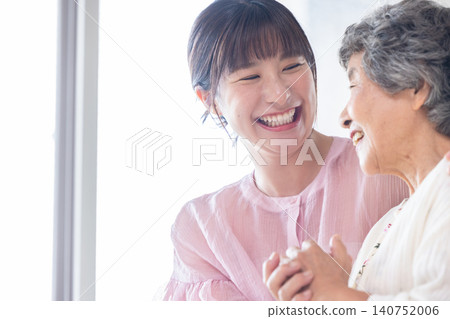 A young woman and a senior woman standing close together 140752006