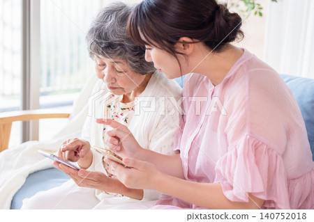Grandchild teaches grandmother how to use a smartphone Grandchild teaches grandmother how to use a smartphone 140752018