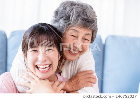 A loving grandmother gently hugs her grandchild from behind. A loving grandmother gently hugs her grandchild from behind. 140752027